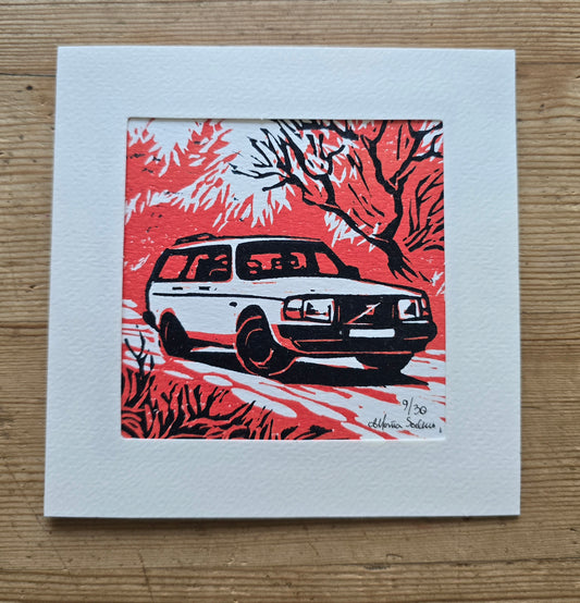 Linotrykk av Volvo 40 stasjonsogn sett forfra, Håndtrykket.med to plater så bildet har tre nyanser.  Hvitt som arket, rødt og svart. Bildet viser bilen og noe vegetasjon rundt. Trykket er montert i passepartoutkort med tilhørende konvolutt.