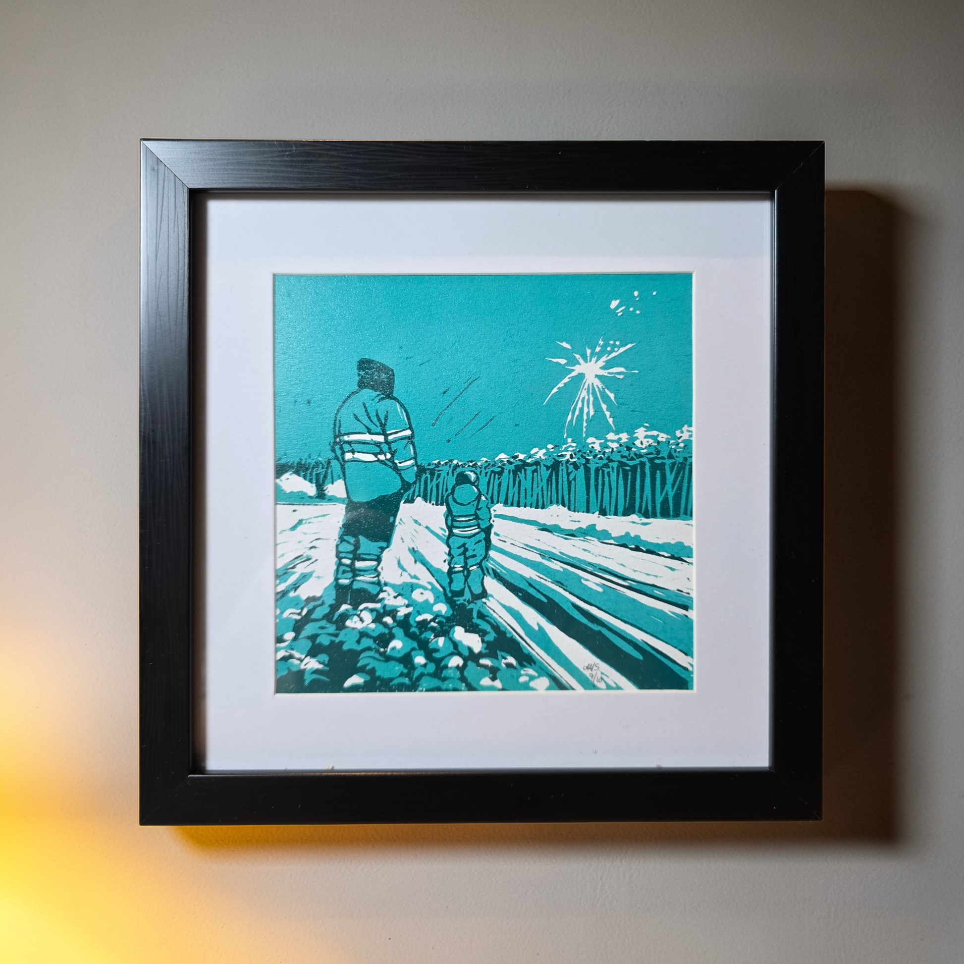 Unikt linotrykk, nummerert 7 av 10. Innrammet i svart ramme av kunststoff. Måler 22 x 22 cm. Motivet er av far og sønn som står sammen og ser nyttårsfyrverkeri, en hyggelig delt opplevelse. Fargene i bildet er mørke og lys grønnblå tone og hvitt i arket. Kunstner monica Sandmo