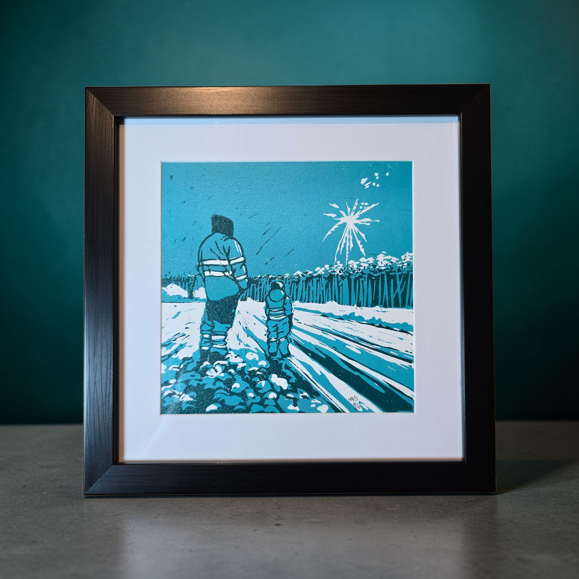 Linotrykk Far og sønn. Dette er nummerert  8 av 10.Trykket viser en far og sønn som står og ser nyttårsfyrverkeri sammen. En koselig stund. Trykket er trykket i blågrønt, mørk og lyst. så er det også hvitt fra arket. Hvit passeopartout og svart ramme i kunststoff.