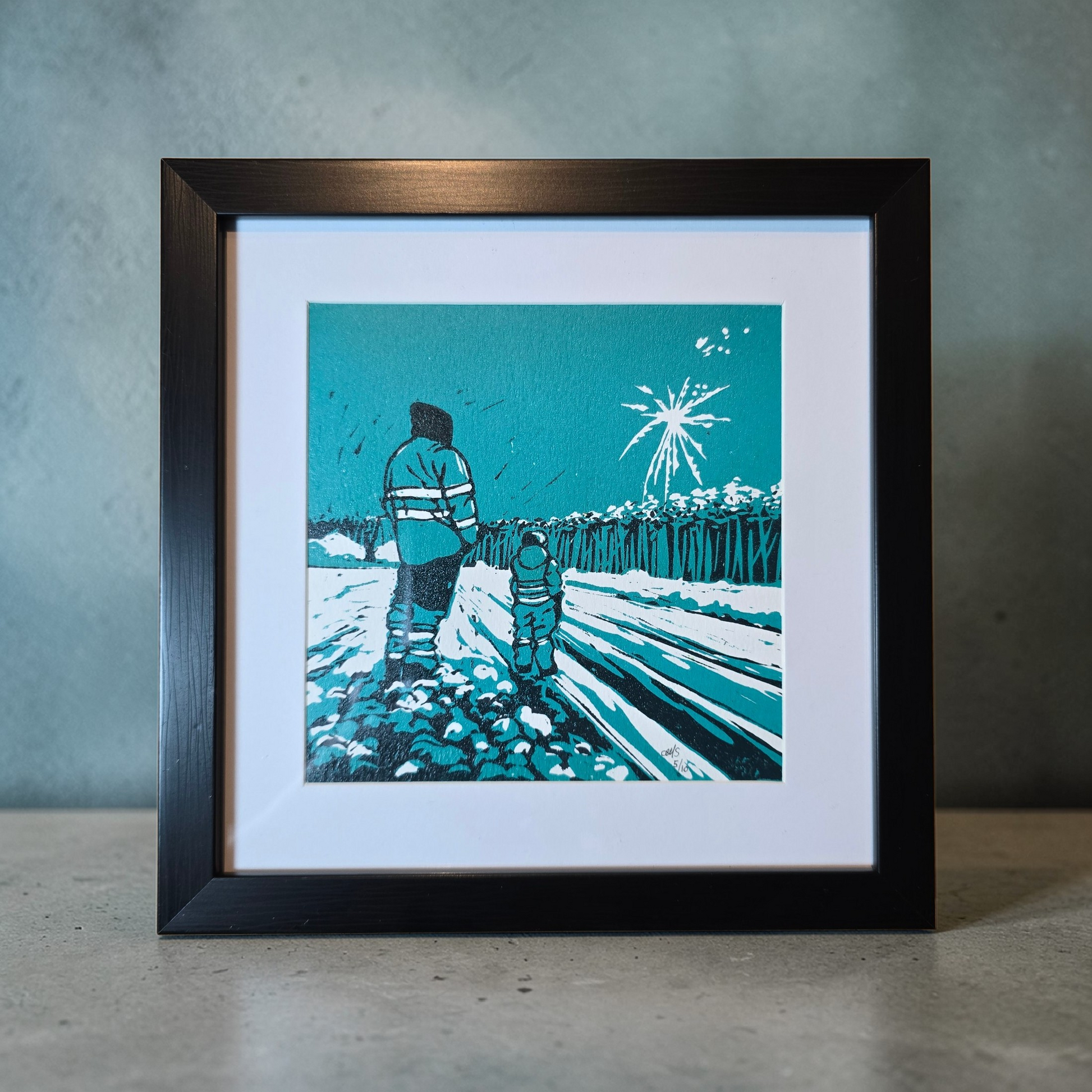 Linotrykk Far og sønn. Dette er nummerert  5 av 10.Trykket viser en far og sønn som står og ser nyttårsfyrverkeri sammen. En koselig stund. Trykket er trykket i blågrønt, mørk og lyst. så er det også hvitt fra arket. Hvit passeopartout og svart ramme i kunststoff.